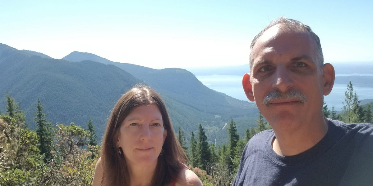 Scenic road winding through mountains with a camper trailer in the distance