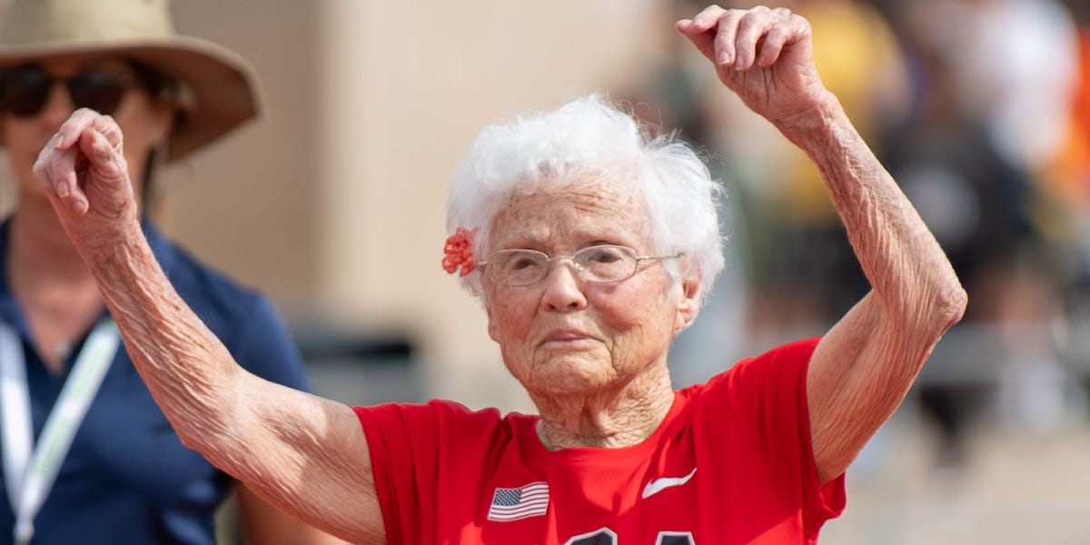 Centenarian woman running along a sunny path surrounded by nature