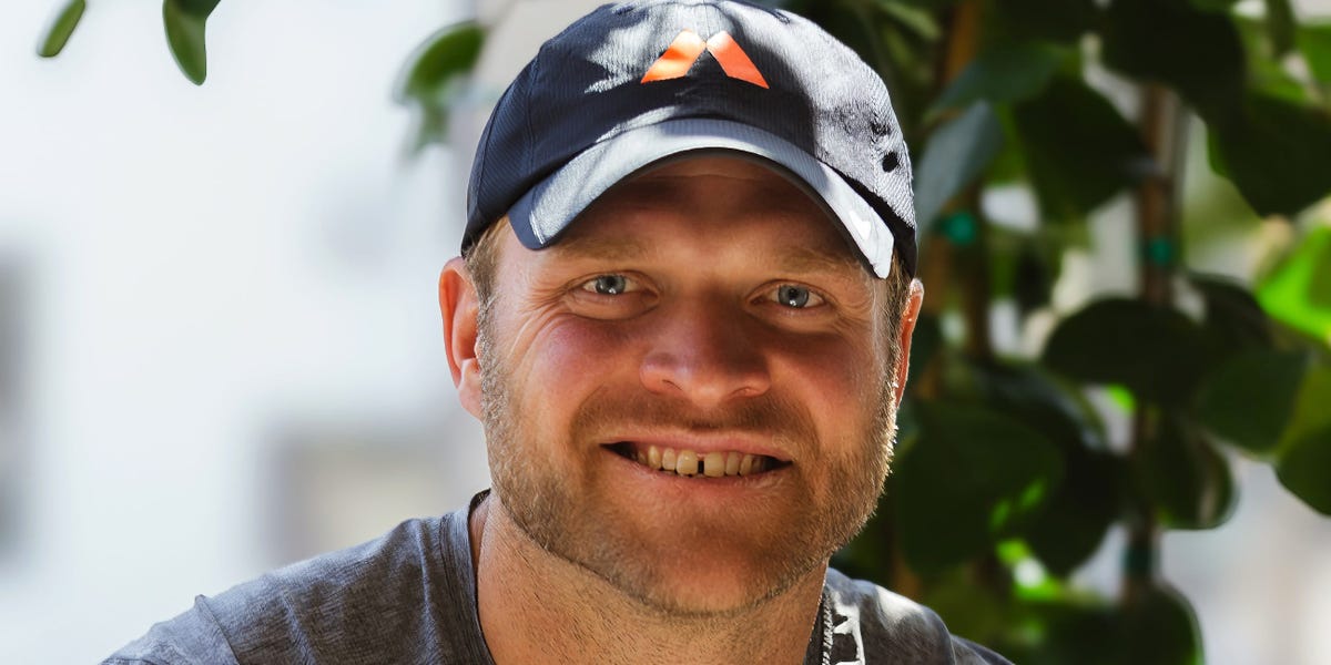 A person walking outdoors with a weighted backpack, taking a business call