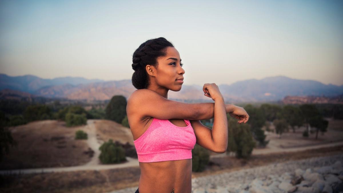 A serene person stretching with a sunrise background