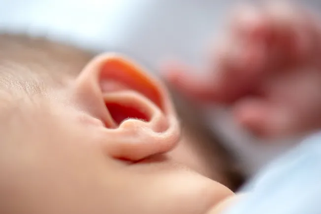 A conceptual image of sound waves restoring hearing in a child inside an abstract ear