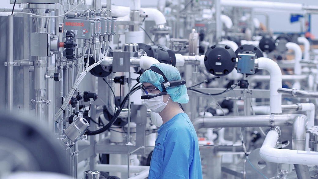 A modern pharmaceutical manufacturing facility with gleaming bioreactors and global connections